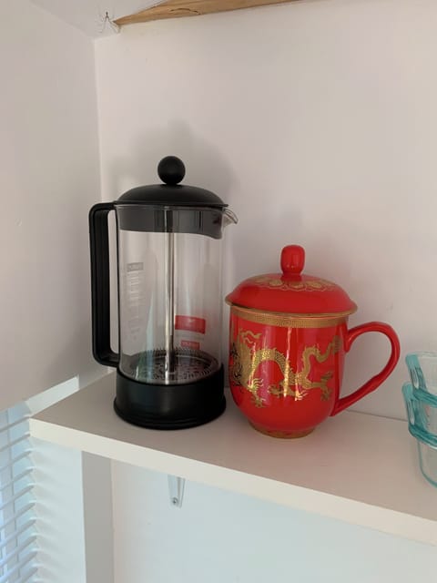French press coffee maker and teacup with tea and lid.