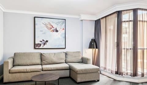 grey fabric sofa decorated with plush cushions, positioned right next to a modern high-top wooden dining table