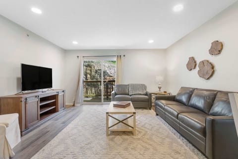 Open living space with ample seating, Smart TV, and balcony access