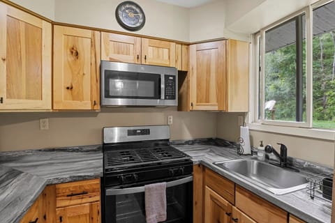 The Main House - Kitchen - Modern kitchen with wooden cabinets, granite countertops, and a window view of lush greenery, perfect for culinary enthusiasts.