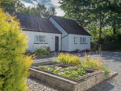 Outside of cottage with raised flower beds and pond