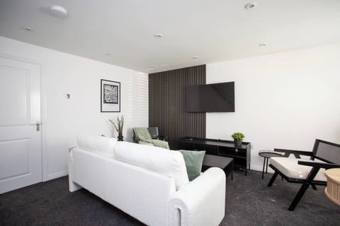 A sleek TV is mounted just in front, providing a perfect spot for relaxation or entertainment, while the minimalist décor enhances the room’s serene and modern vibe.