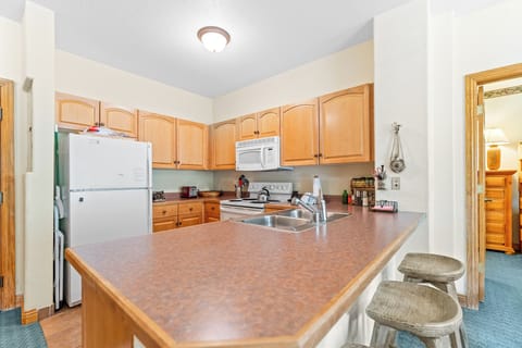 Full kitchen with dishwasher and breakfast bar with seating for three.