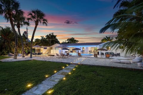 "Evening Bliss: Follow the Illuminated Path to Discover the Serenity of This Stunning Waterfront Retreat, Perfect for Relaxation and Enjoying the Sunset."