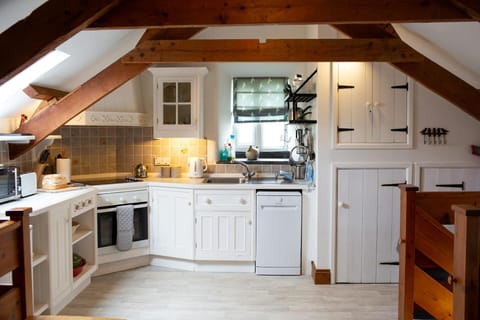 Fitted kitchen with white cupboards and wall cupboard. oven, dishwasher, kettle and microwave
