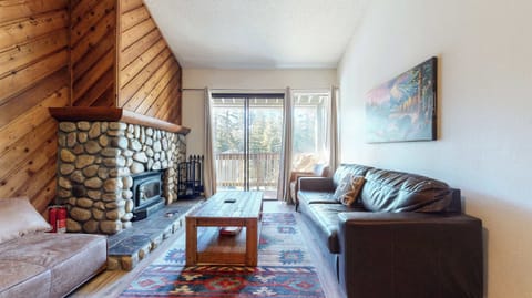 Open living space with sofa, sleeper, TV, fireplace, and balcony