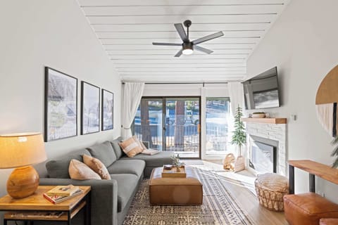 Living room with TV, gas fireplace, balcony access, and sofa sleeper