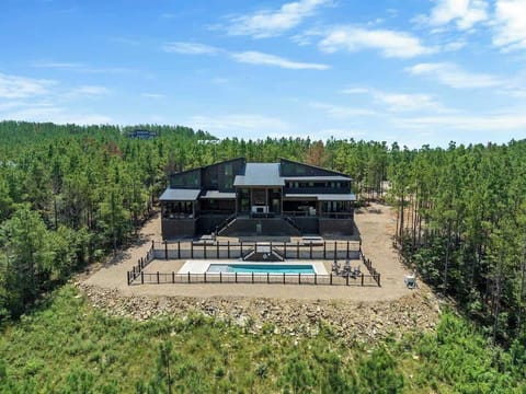 Drone view of luxury cabin with private pool, multiple decks, and forest surroundings in Mountain Fork Resort.