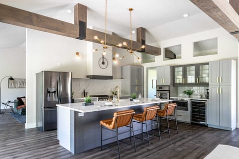 The spacious kitchen has a 10 foot quartz island, 6 burner professional gas range, additional double wall ovens, a wine fridge, and lighted glass front cabinetry.