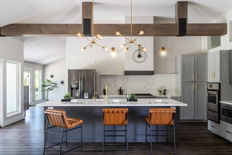 The spacious kitchen has a 10 foot quartz island, 6 burner professional gas range, additional double wall ovens, a wine fridge, and lighted glass front cabinetry.