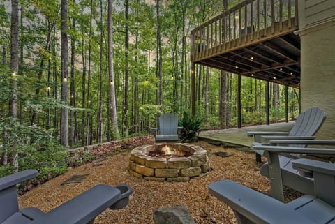 Enjoy a seat in one of the inviting Adirondack chairs surrounding this stone fire pit, nestled within a tranquil forest setting. This peaceful outdoor area, shaded by tall trees, offers a perfect spot to relax and immerse yourself in nature's beauty.