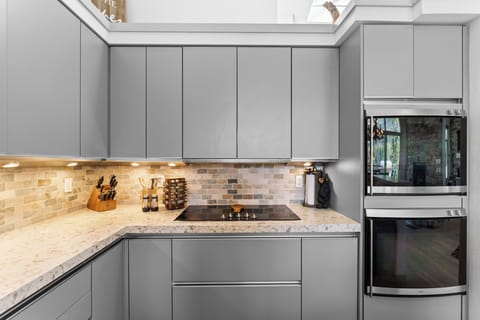 Full kitchen featuring granite countertops, induction stovetop, double wall oven, and an integrated refrigerator blending into the cabinetry.