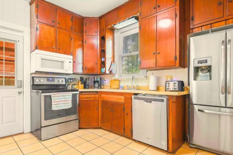 A well-coming fully stocked kitchen w/ orange cabinetry and modern appliances