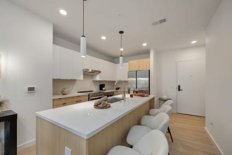 Unit 1: Fully equipped modern kitchen stocked with all culinary essentials and featuring brand new stainless steel appliances with an island offering bar seating.