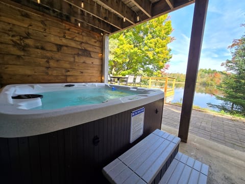 Unwind in our covered lakeside hot tub with stunning views! ✨ Enjoy bubbling water, peaceful nature, and vibrant trees—perfect for sunrise coffee or a relaxing sunset soak. 🌲🌅