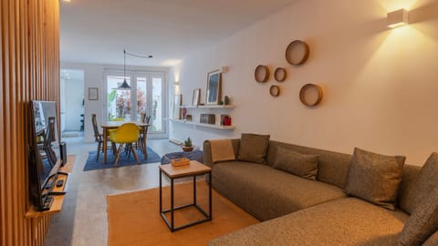 A bright space with a comfortable sofa, minimalist decor, and a vibrant dining table that opens onto the patio. #decor #apartment #lisbon #airbnb