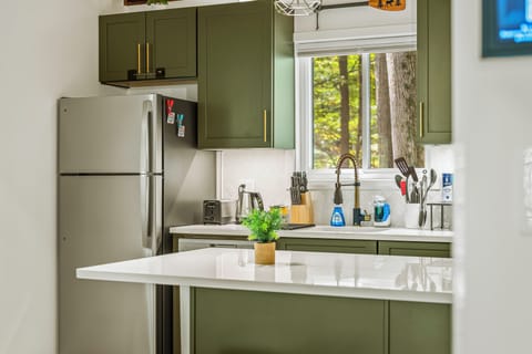 Kitchen features stainless steel appliances and beautiful green cabinetry.