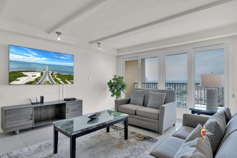 The living room area has plush sofa seating and a wall-mounted flatscreen Smart TV.