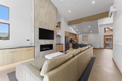 Top floor living area with ample seating, fireplace, dry bar with wine fridge, and large windows with stunning views.