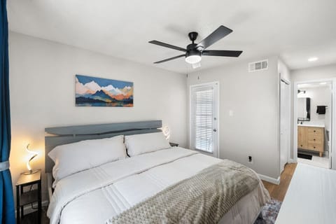 Primary Bedroom with King bed, balcony access door, private bathroom, laundry closet, walk-in closet, ceiling fan, Nightstands with USB and plugs, and clothing dresser storage.