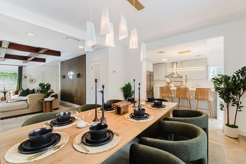 This spacious and modern dining room features ample natural light, creating a vibrant atmosphere. The wooden table adds warmth, while the comfortable green chairs invite relaxation during meals.