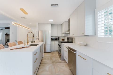This spacious, modern kitchen features sleek white cabinetry and a bright, open layout. The contemporary design invites creativity and makes cooking a pleasure.