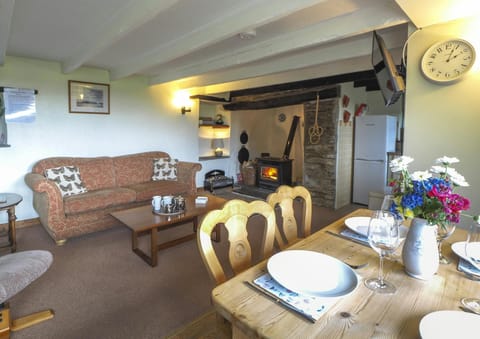 Two seater sofa, coffee table, side table, log burner, dining table laid for four and fresh flowers.