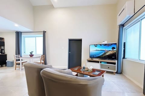 A spacious and well-lit living room featuring comfortable armchairs and a television.