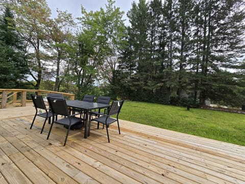 - Dine outdoors on this wide deck with forest views   - Comfortable seating makes meals feel refreshing   - A serene backyard setup perfect for gatherings