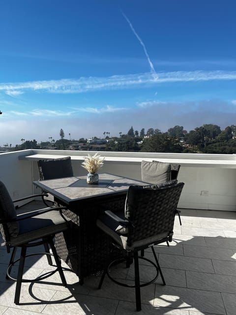 Outdoor dining table with fire pit on back deck with ocean and sunset views.