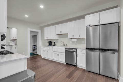 Large fridge, a farmhouse sink, and elegant dark wood floors.