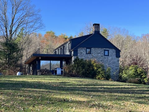 Back view of the house with modern extension, back patio, and rooftop deck