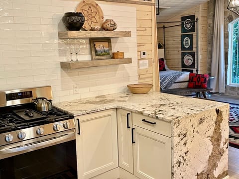 A full kitchen with granite waterfall peninsula with extra seating and gas range