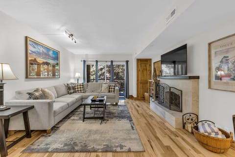 Living Room: L-shaped sleeper couch, a wood-burning fireplace, 55” Smart TV w/cable, access to the balcony