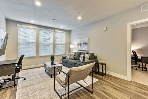 Bright living area w/ cozy sofa seating, desk nook & large windows bringing in natural light