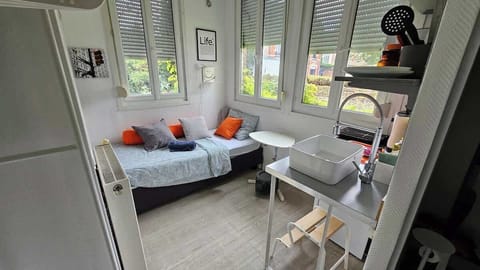 Espace chambre avec un lit simple et télévision.
L'espace de vie est ouvert sur la kitchenette.