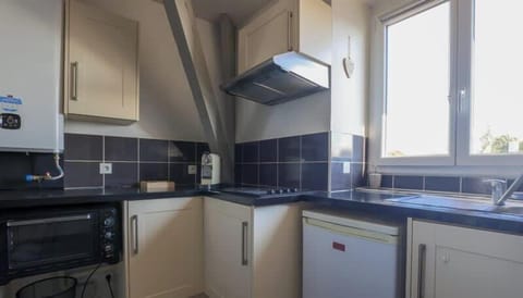 Cuisine équipée avec petit réfrigérateur, machine à café, bouilloire, plaques de cuisson et micro-ondes faisant four.