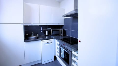 Cuisine équipée avec réfrigérateur avec freezer, lave-vaisselle, micro-ondes, machine à café, bouilloire, plaques de cuisson et four.