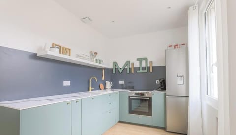 Cuisine équipée avec four, plaques de cuisson, machine à café, bouilloire, réfrigérateur avec partie congélateur, lave-vaisselle, machine à laver et micro-ondes.