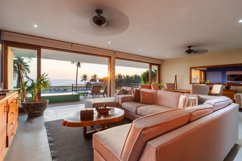 Experience seamless indoor-outdoor living with this beautifully designed lounge area featuring plush seating and stunning sunset views.
