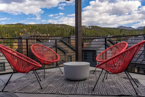 - Stunning rooftop seating area with panoramic views of the mountains
- Three modern red chairs surround a sleek round table on an outdoor rug
- Ideal place to unwind while enjoying the crisp mountain air