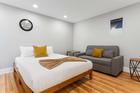 Bright and spacious first-floor queen bedroom featuring modern decor, comfy bedding, and a cozy sofa—perfect for relaxing after a long day