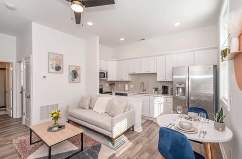The bright open layout brings the living room, dining area, and fully equipped kitchen together, with a comfy sofa, café seating for two, and modern furnishings.