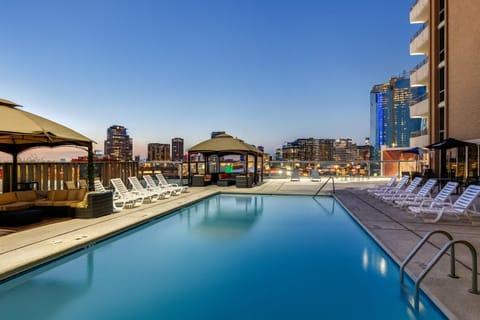 Unwind poolside at dusk with sparkling city skyline views
