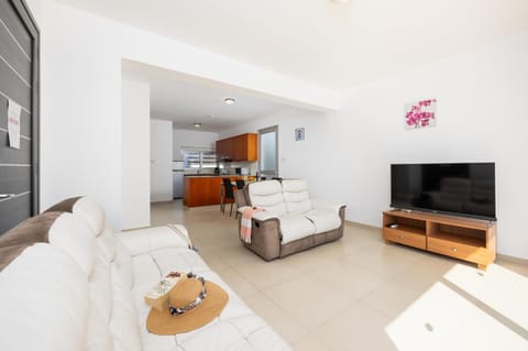 Open-plan living room with sofas, dining area, kitchen, A/C, WiFi internet, and satellite TV