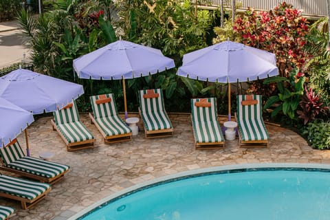 Relax poolside in a serene environment, surrounded by vibrant foliage and colorful umbrellas, offering a peaceful escape.