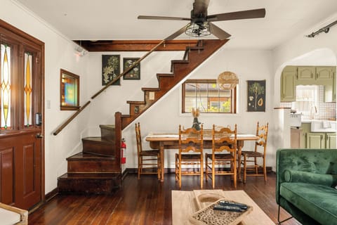 - Step inside to warm wood tones, vintage charm, and a unique staircase design
- The dining nook beneath the stairs makes clever use of space
- Ceiling fan, natural textures, and stained glass windows add personality
