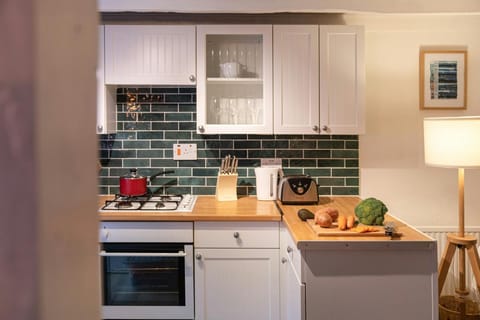 Kitchen with electric oven and gas hob, wooden work surfaces, kettle and toaster