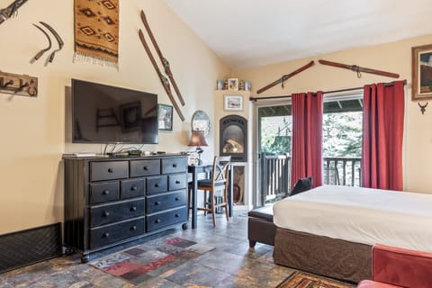 Open studio space featuring a comfortable queen bed, flat-screen TV, and cozy mountain décor.