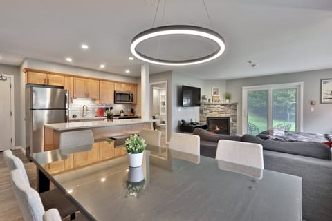 A cozy living area to unwind, with a fireplace and forest views, and a fully-equipped open kitchen to enjoy your meals.